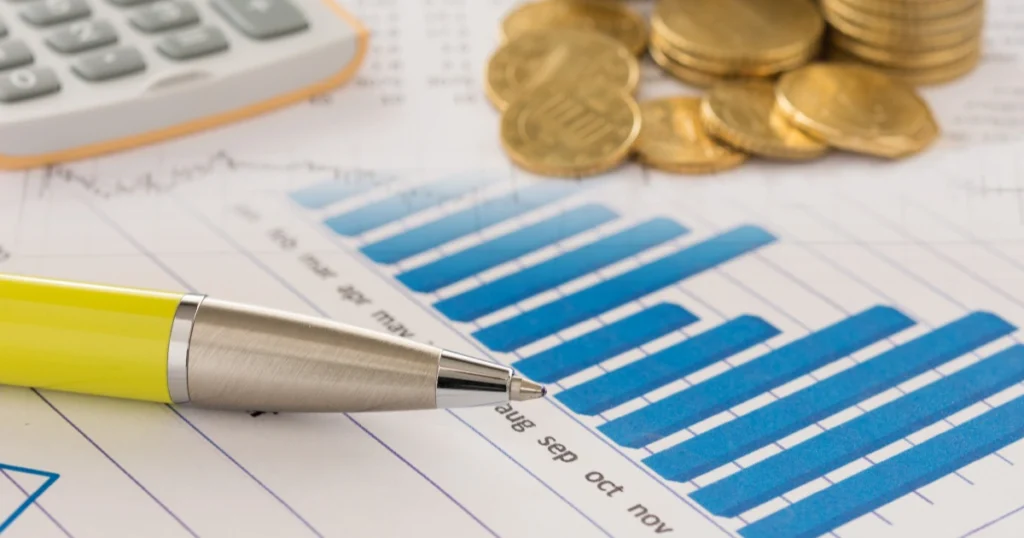 Diagramme statistique ? barres bleues avec des pi?ces d'euros et une calculatrice, illustrant l'analyse financi?re d'un investissement dans un second bien immobilier.