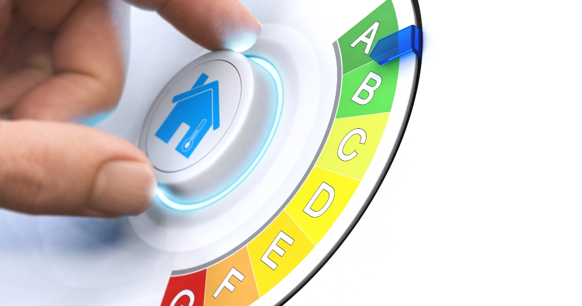 Primer plano de una mano ajustando un dial con el icono de una casa hacia la calificaci?n de eficiencia energ?tica 'A' en una escala de colores de la A a la G.