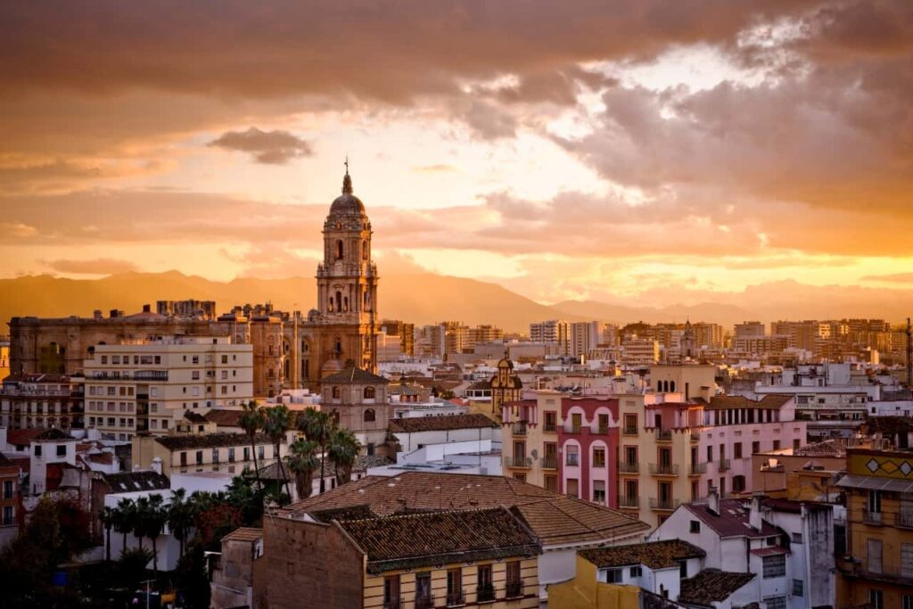 Aerial snapshot of Malaga city in a cloudy sunset with orange sky.