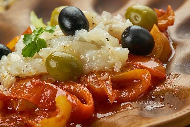 Close-up van een esgarrat uit Alicante: geroosterde paprika's, verkruimelde kabeljauw, zwarte olijven, knoflook en olijfolie.