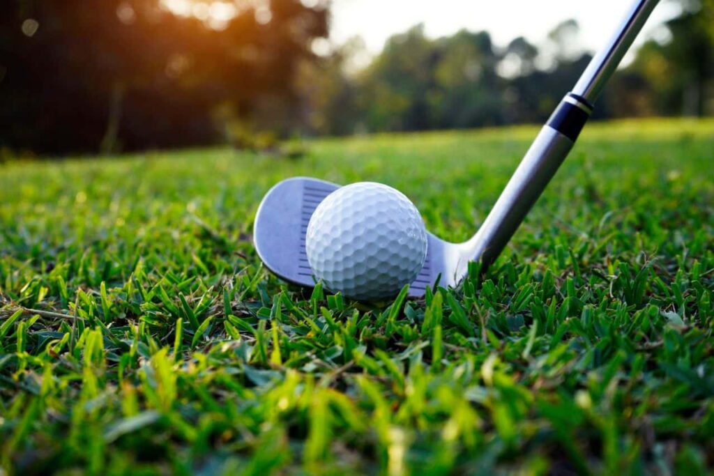 Golfclub op de voorgrond die een bal duwt op een van de banen aan de Costa del Sol.