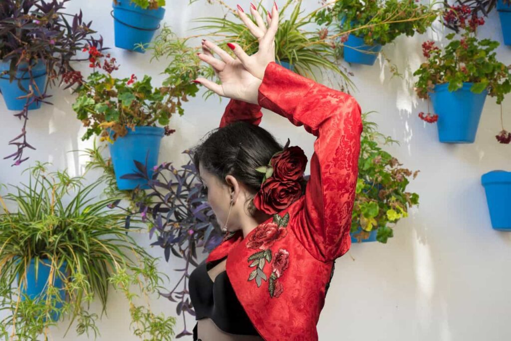 Mujer vestida de flamenca bailando en un partio andaluz.